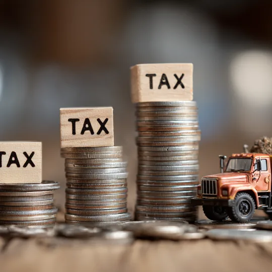 barndominium tax savings concept with stacked coins tax labels and construction truck