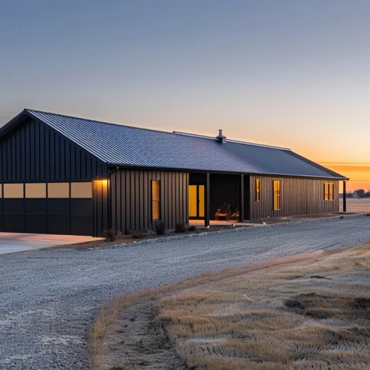 modern dark metal barndominium flip project on rural land with gravel driveway and garage at sunset